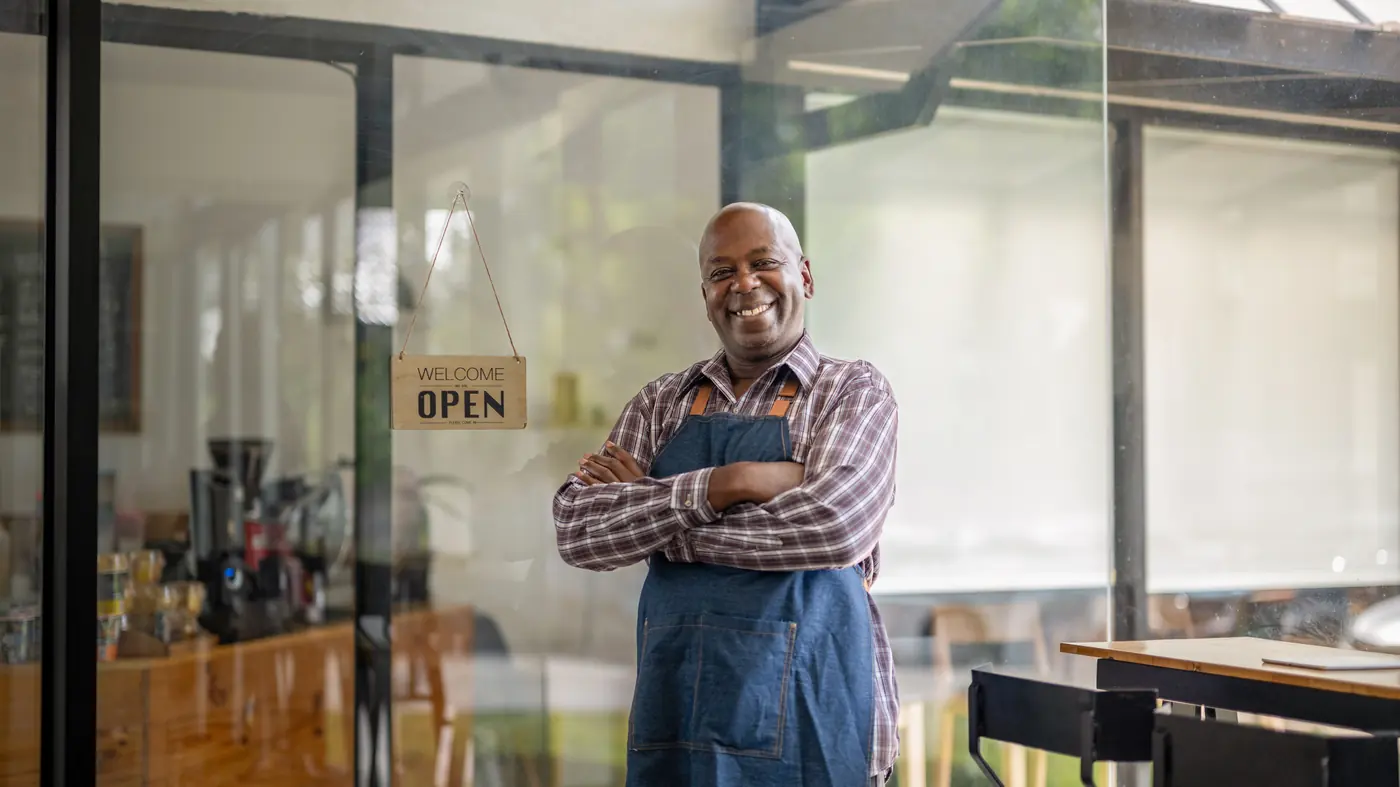 Small business owner standing in the doorway of his open shop